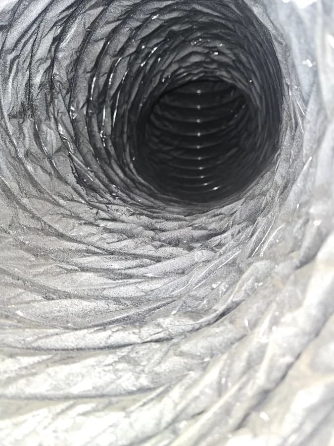 Dust buildup visible inside a flexible air duct pathway