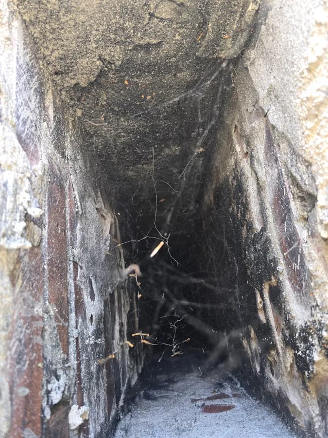 Debris and cobwebs visible inside a chimney flue